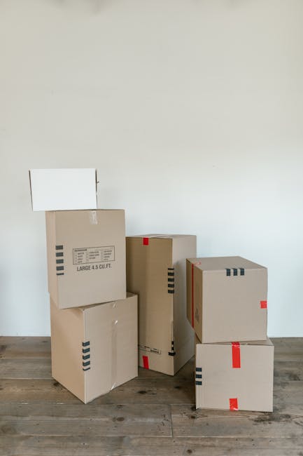 A collection of packed luggage and travel bags placed on the ground near the open door of a van, which is used for home relocation or long-distance moving. The luggage includes a grey hiking backpack